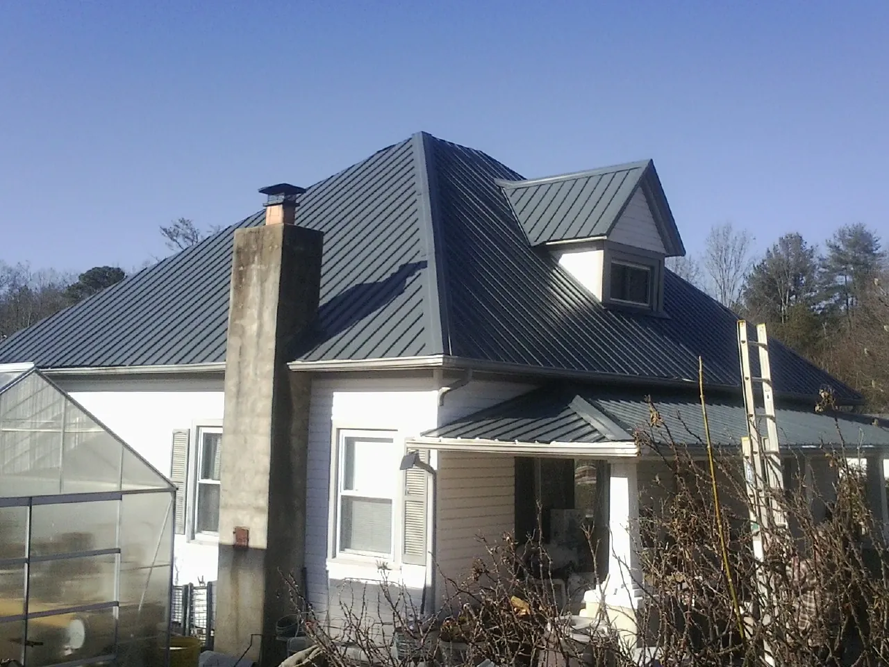 Dark blue standing seam metal roof on a white farmhouse with dormer — Slate & Tile Roof Repair by Roofing Brothers in Tinley Park