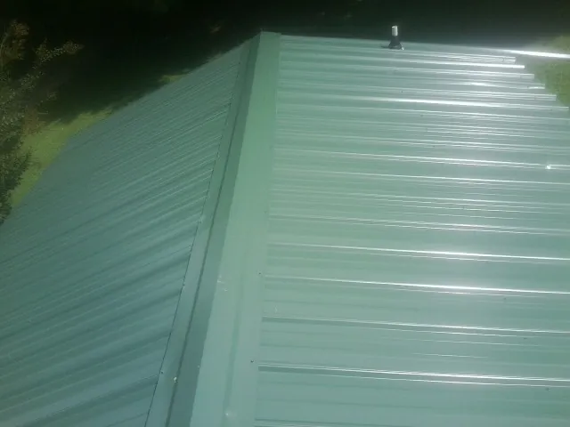 New green metal panels meeting at the ridge of a roof — Flat Roof Repair work by our crew in Tinley Park