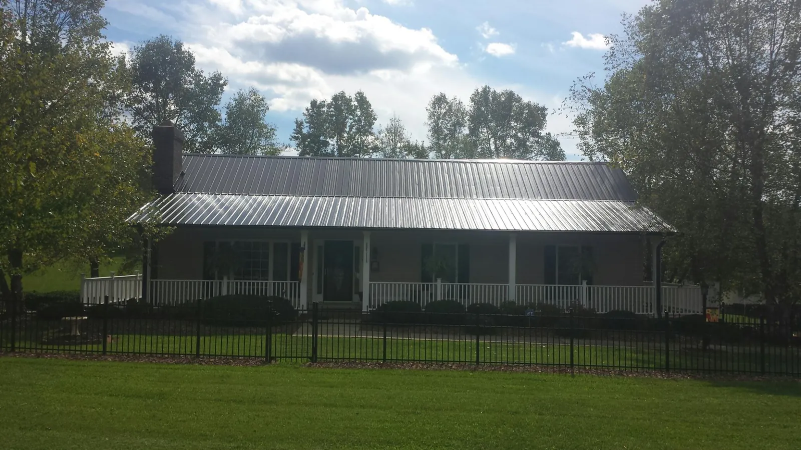 Gray metal roof on a brick ranch with a full width front porch — Gutter Guard Installation work by our crew in Tinley Park
