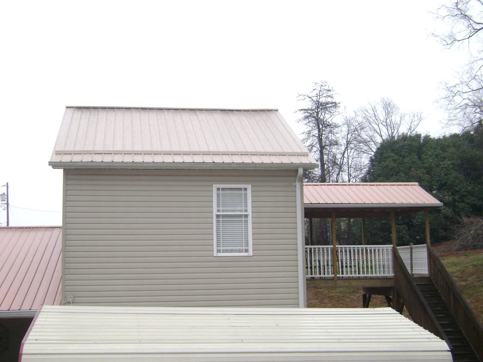 Tan metal roofs on a two story addition and attached porch, from a Roof Replacement job in Tinley Park