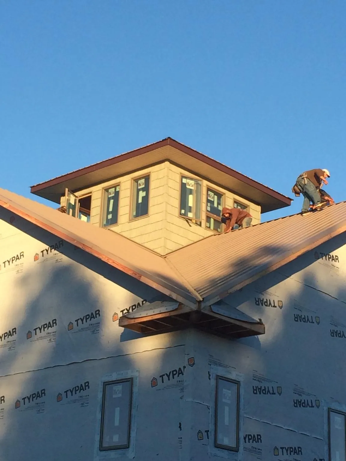 Roofers working around a rooftop cupola on a new metal roof at sunset — Roof Waterproofing in Tinley Park by Roofing Brothers